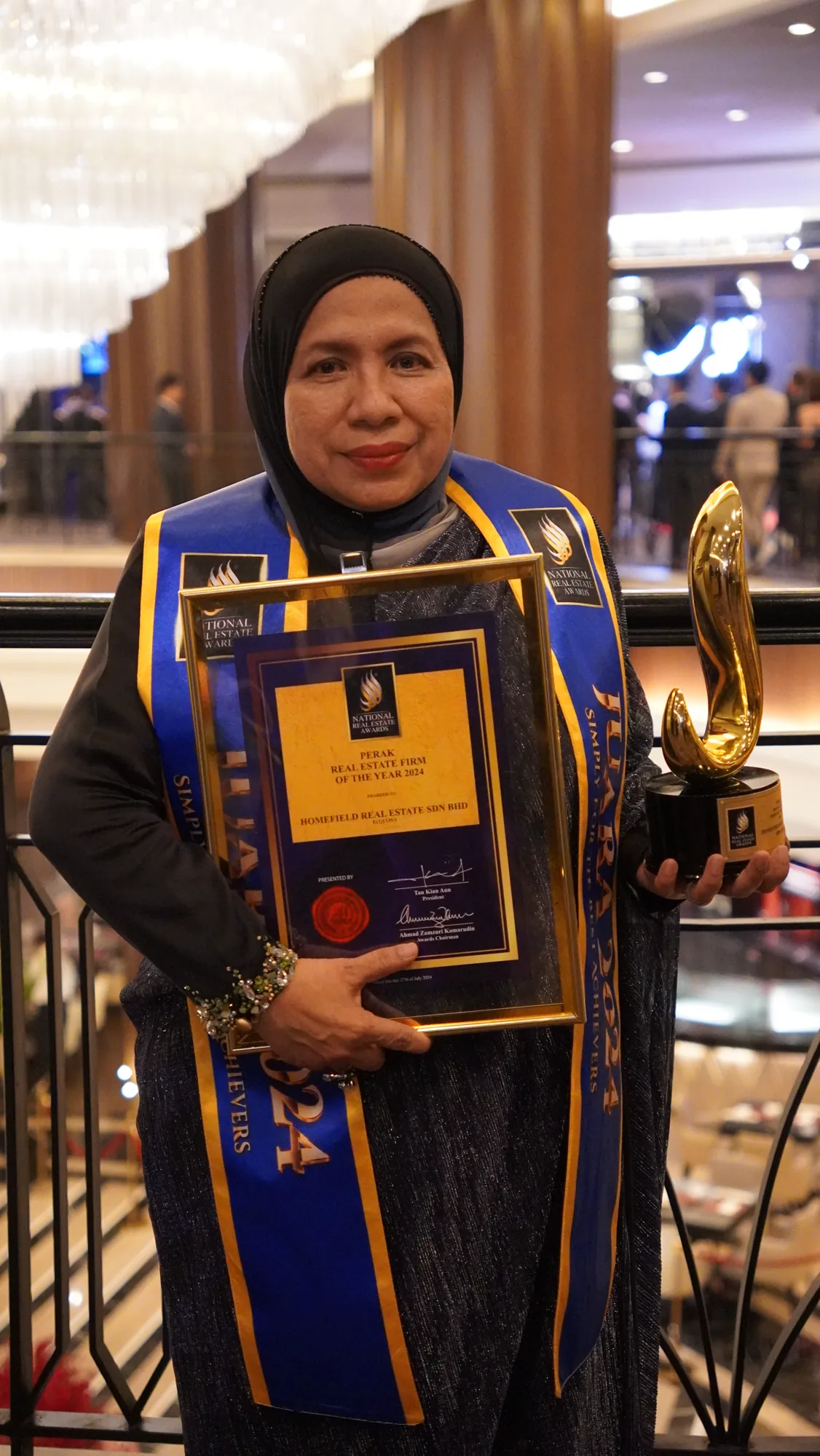 Munirah Mohammad holding Homefield's 2024 Perak Real Estate Firm of the Year award and trophy